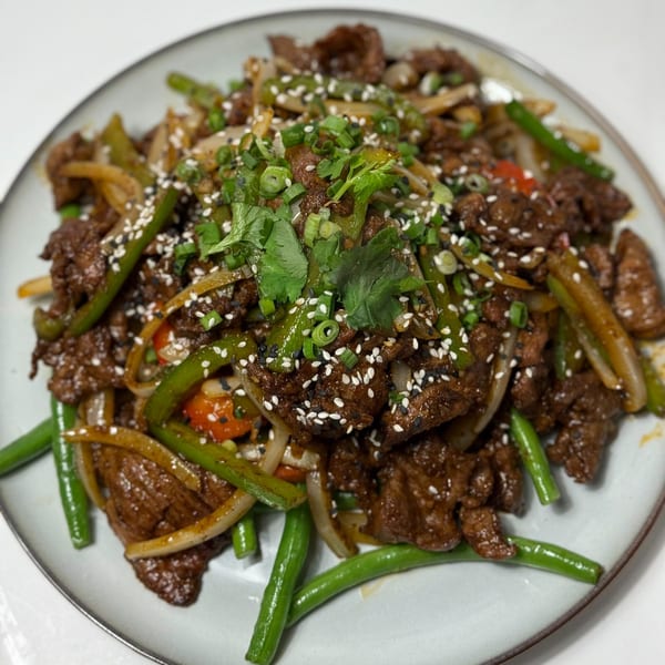 Close-up of Silk Road Uyghur Cuisine's halal beef stir-fry with green beans, onions, and sesame seeds.